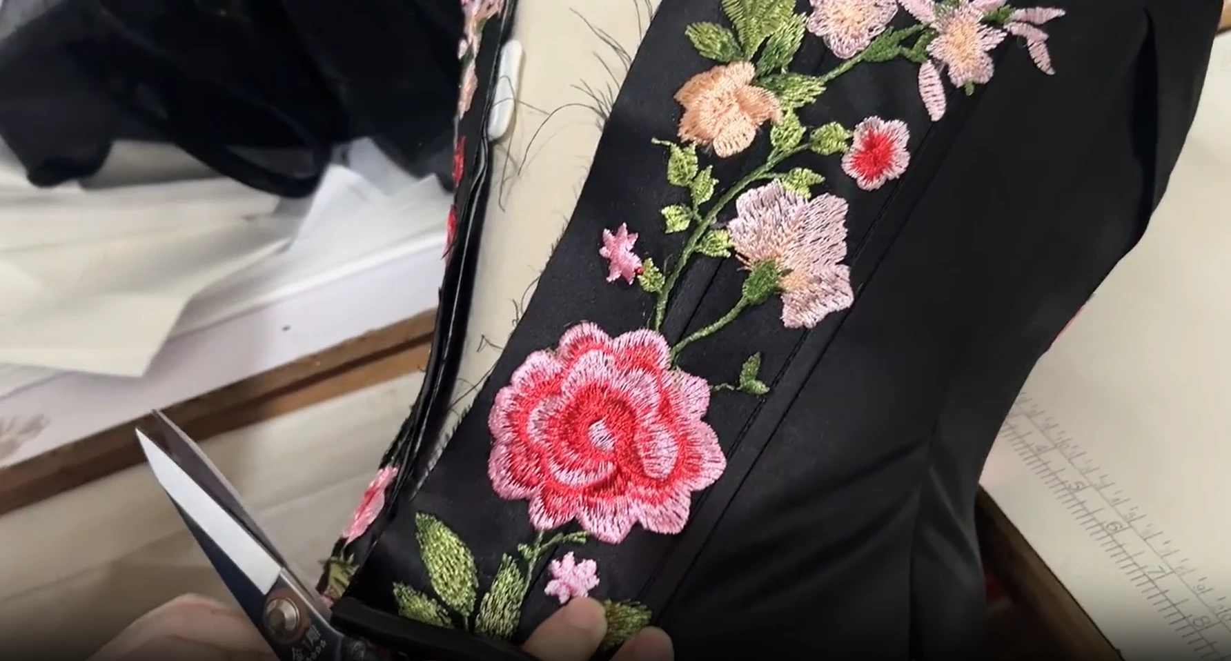 Trimming the edge of an embroidered gown panel by hand