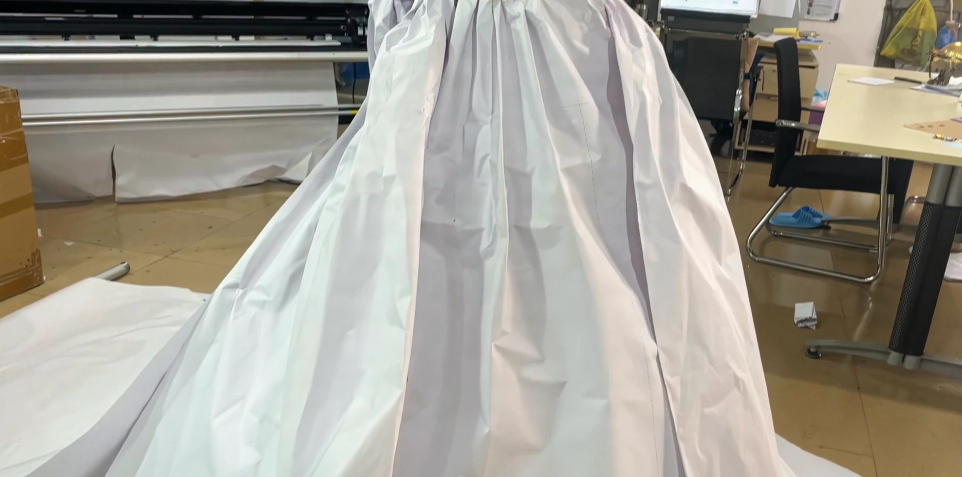 White muslin fabric laid out on the workroom floor for the initial pattern drafting of the champagne pink gown