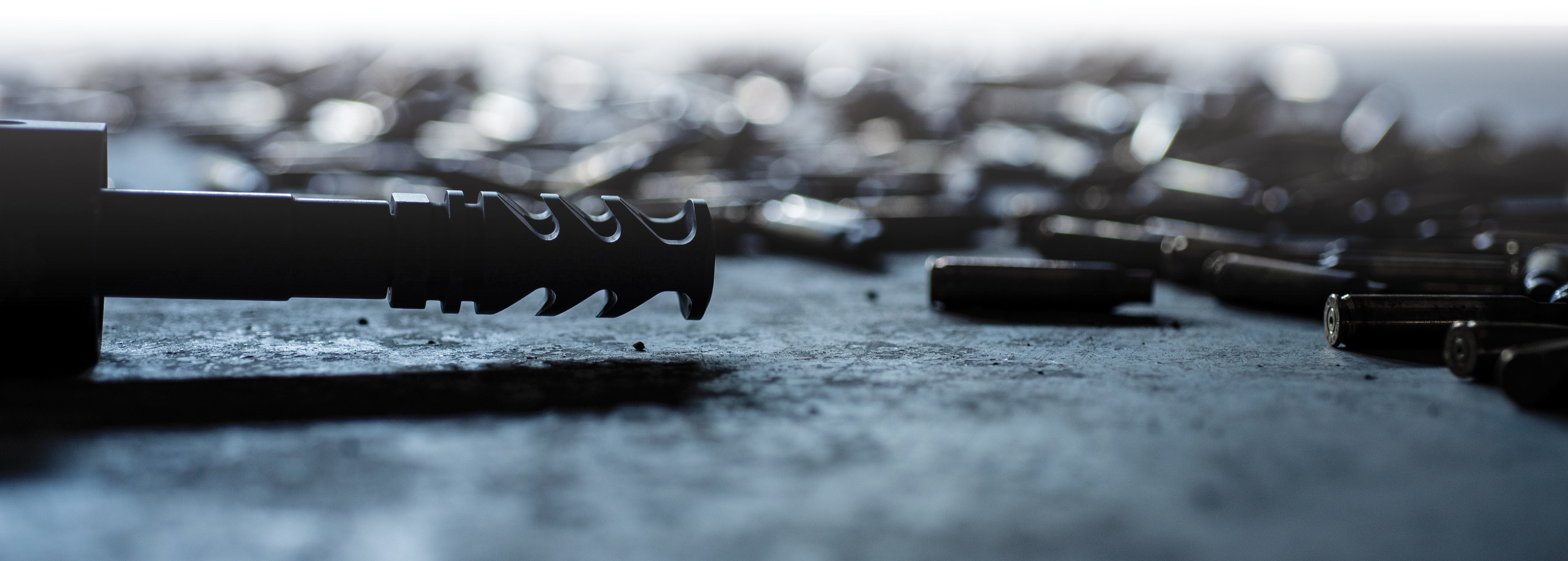 silhouette of M4-72 Severe-Duty Muzzle Brake surrounded by spent ammo casings