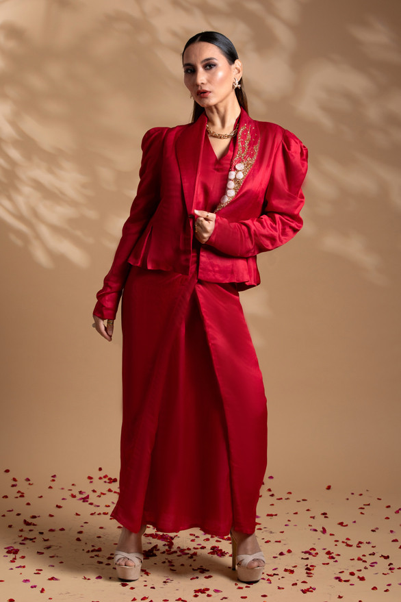 Kashesh Global Pataka Ensemble: A striking scarlet red overlap dress in a linen-satin blend, worn with a structured puff-sleeve statement jacket featuring genuine rose quartz hand-embroidery