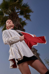 Kashesh Maham Coat in Ivory: A cream and gold handwoven mid-length women's jacket featuring dramatic shoulders and gold sequin embroidery reading 'Impossible' and 'Dream,' revealed against a luxurious red silk lining