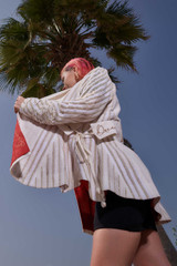 Kashesh Maham Coat in Ivory: A cream and gold handwoven mid-length women's jacket featuring dramatic shoulders and gold sequin embroidery reading 'Impossible' and 'Dream,' revealed against a luxurious red silk lining