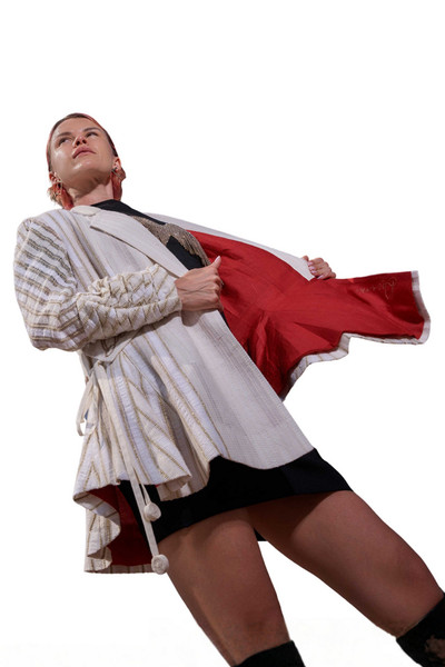 Kashesh Maham Coat in Ivory: A cream and gold handwoven mid-length women's jacket featuring dramatic shoulders and gold sequin embroidery reading 'Impossible' and 'Dream,' revealed against a luxurious red silk lining