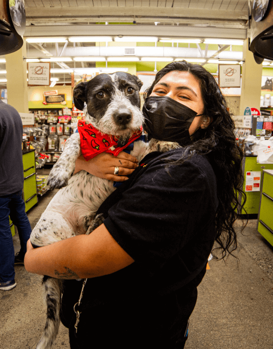 A Pet Food Express employee holding a dog.