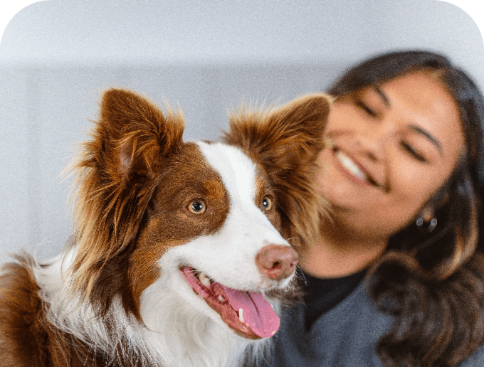 Smiling woman stands behind dog