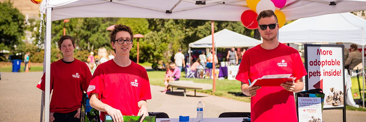 Pet Food Express employees in red shirts at Bay Area Pet Fair booth