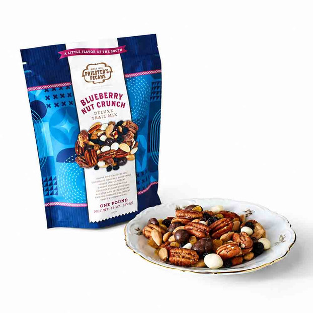 Priester’s Pecans Blueberry Nut Crunch Trail Mix, 1 lb bag, with a plate of pecans, almonds, dried blueberries, and yogurt raisins