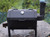 This handcrafted tabletop smoker grill is built from 10-gauge steel and finished with high heat BBQ paint for a durable, long lasting black finish. It features coal and cooking grates, a vent door, stack cover, and comes equipped with a built-in thermometer for precise temperature control. Designed to perform exceptionally well in windy conditions, making it a great choice for outdoor cooking in any weather. Handle includes a spring for safe and easy use.