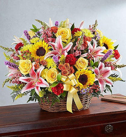 Custom funeral basket arrangement with fresh flowers placed beside a casket for a celebration of life service by Wendy's Flowers in Gilbertsville, PA.