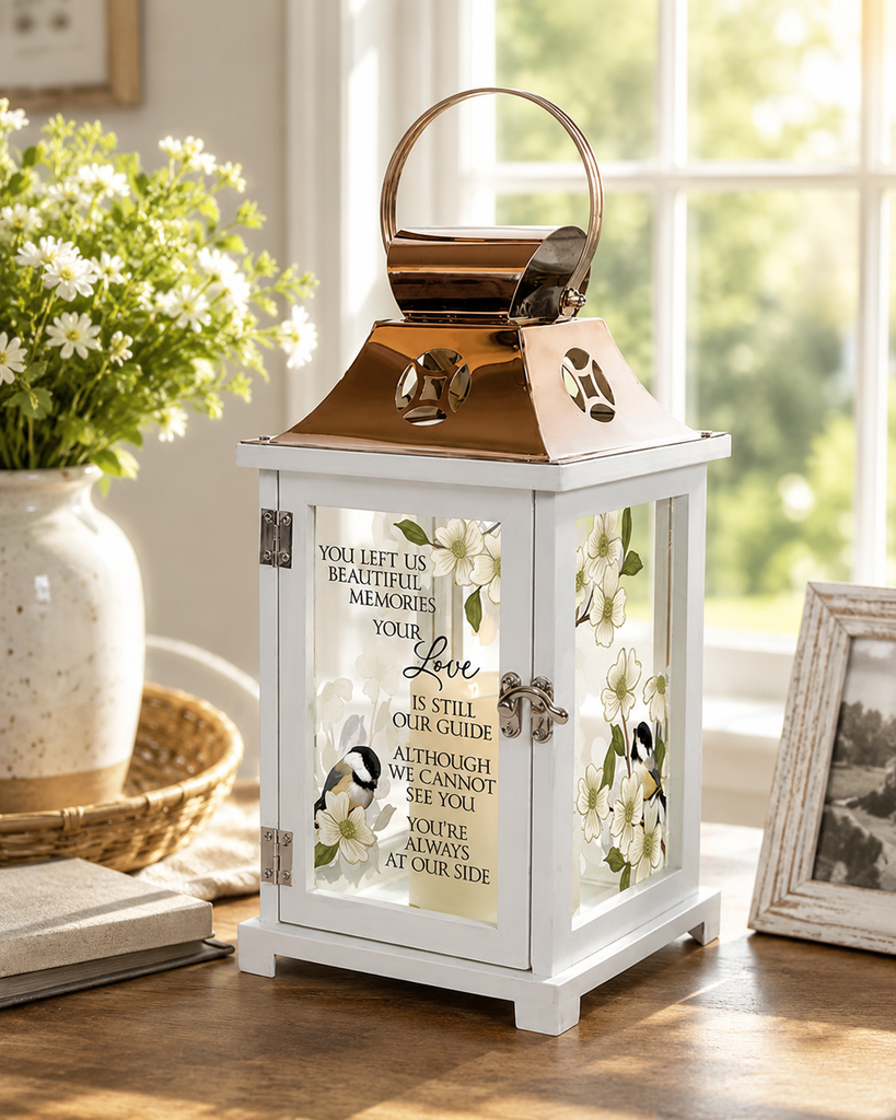 White memorial keepsake lantern with a stainless steel copper finish top and inspirational sentiment, displayed on a table in a peaceful home setting with natural sunlight and soft floral accents.