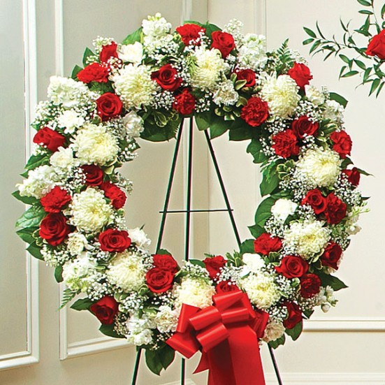 Elegant sympathy wreath with red roses, white flowers, and baby's breath in a funeral setting