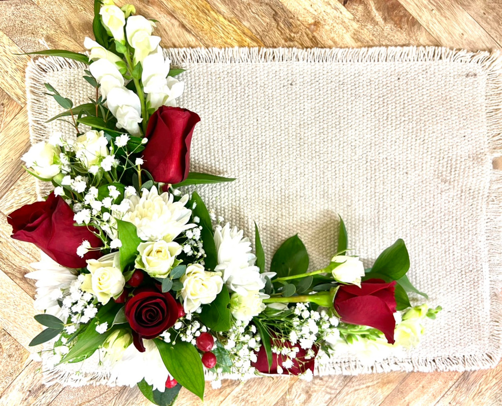 Handcrafted sympathy flower arrangement displayed along the interior edge of a funeral casket