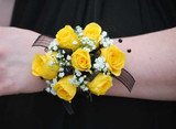Yellow rose wrist corsage with soft greenery accents