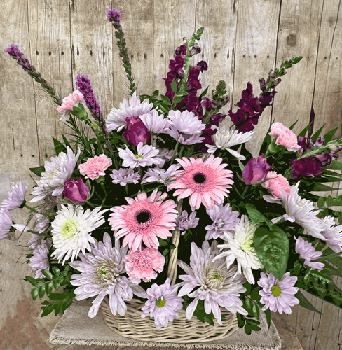 Sympathy funeral basket displayed next to a casket with fresh seasonal flowers for funeral and memorial services by Wendy's Flowers in Gilbertsville, PA.