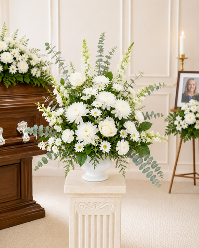 Custom color funeral pedestal arrangement featuring fresh seasonal flowers and greenery, professionally designed as a personalized sympathy tribute