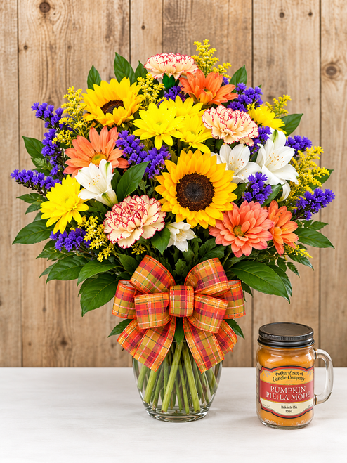 Fall floral arrangement with sunflowers, colorful seasonal flowers, plaid bow, and pumpkin candle at Wendy’s Flowers.