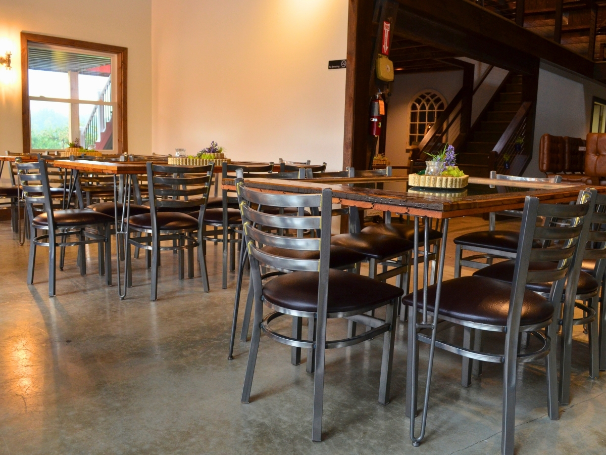 Metal dining chairs with black vinyl seats paired with wood tables in a restaurant dining room