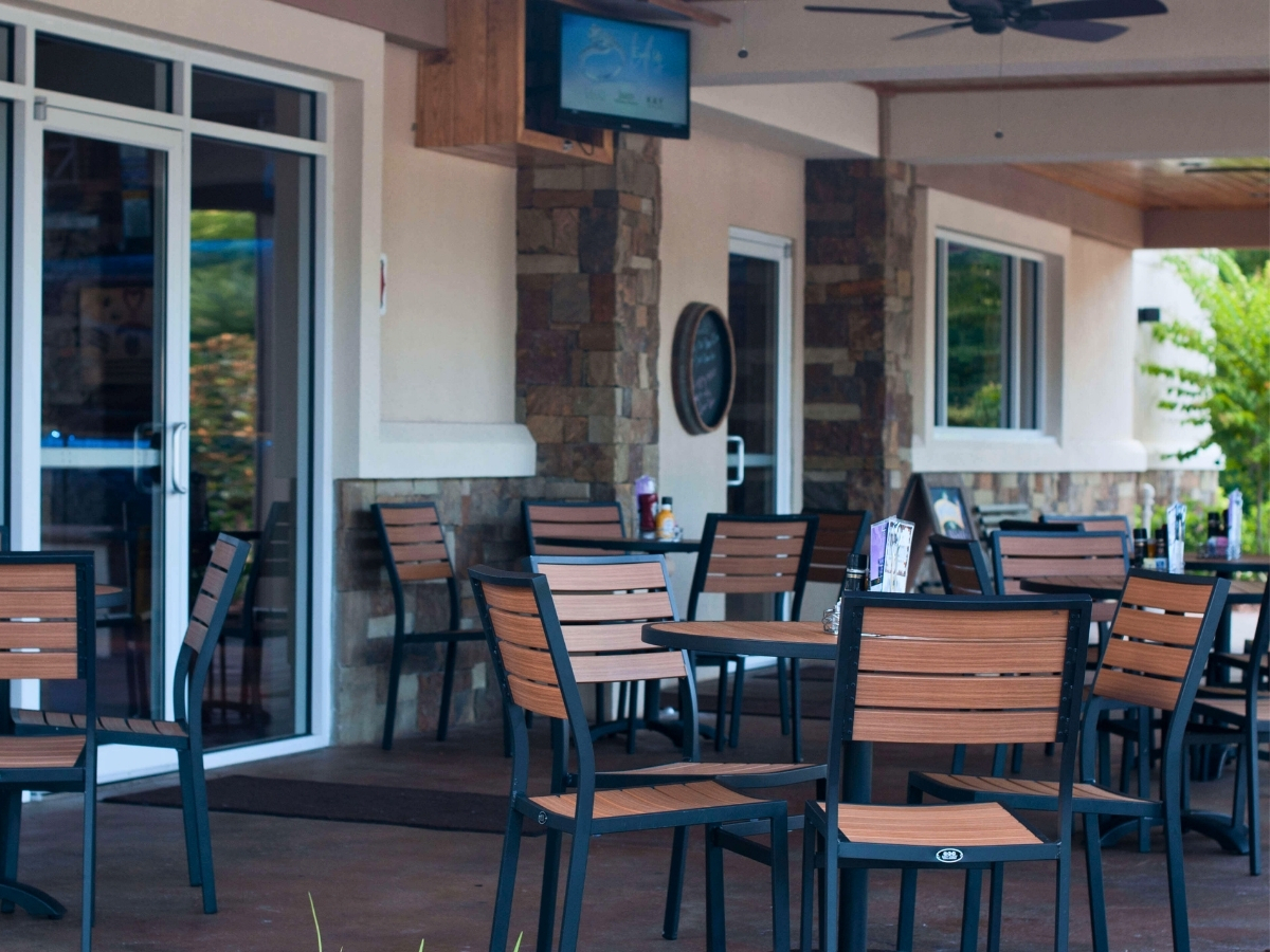 Outdoor restaurant patio with wood slatted chairs and tables for commercial hospitality seating