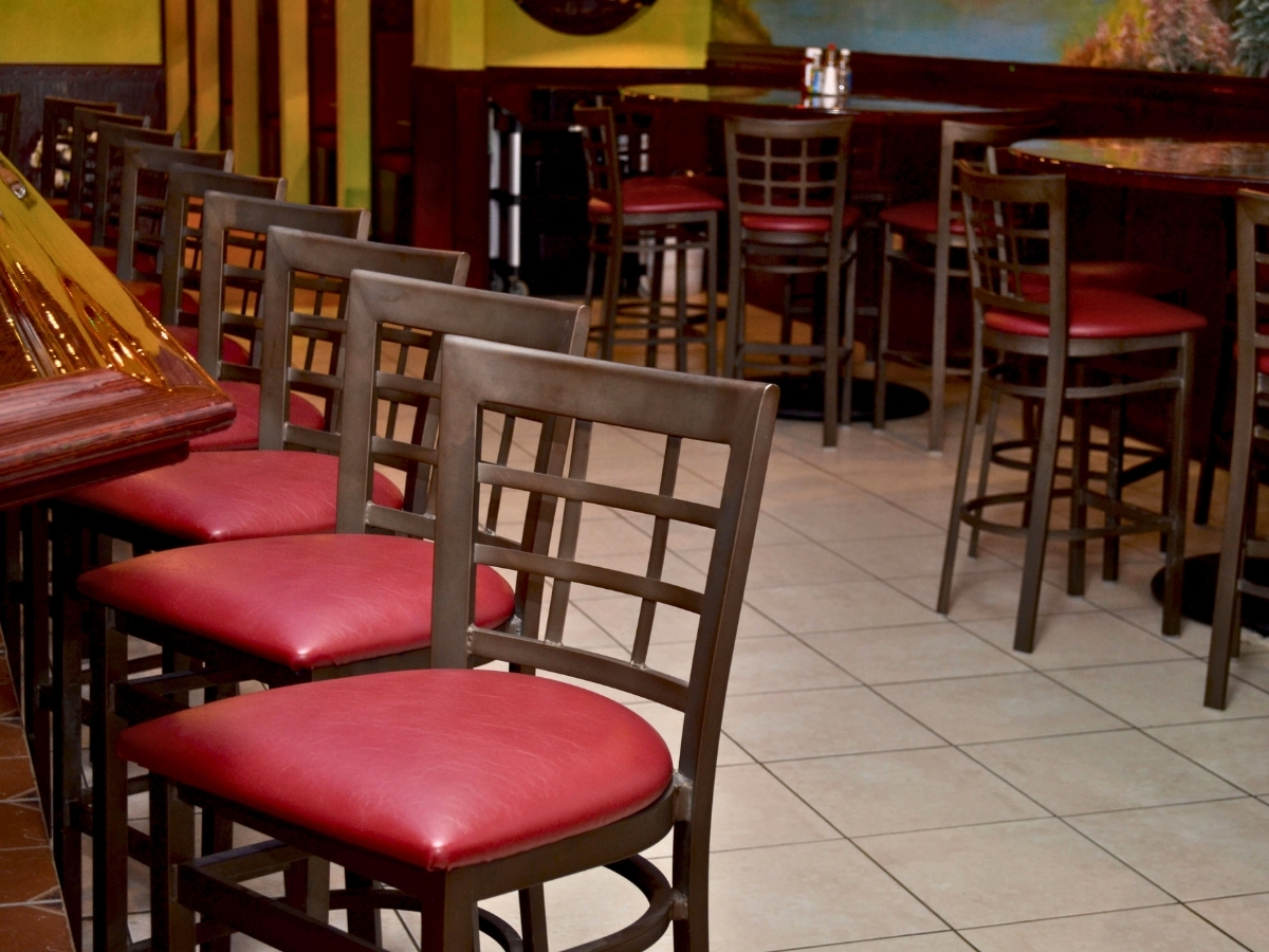 Industrial metal bar stools at a modern restaurant bar with wood paneling and stainless countertop
