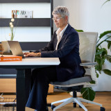 Konzentriertes Arbeiten auf dem ofinto Active Bürostuhl - Business-Frau am Laptop mit ergonomischem Premium-Stuhl in hellem Design