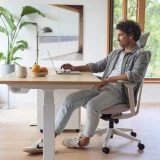ofinto Active Bürostuhl mit Elevate Schreibtisch - Mann arbeitet ergonomisch am Laptop auf höhenverstellbarem Tisch mit Stehmatte