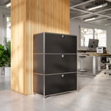 Cubox Büroregal mit 3 Ebenen und 3 Klappen in Schwarz vor Holzlamellensäule im modernen Großraumbüro mit Schreibtischen