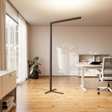 Büro-Stehlampe Lumino Pro in Schwarz, in hellem Büro mit Holzboden und Schreibtisch