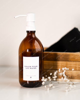 Flacon distributeur en verre ambré à pompe blanche, étiquette Savon pour les mains, devant une cagette en bois et un brin de gypsophile