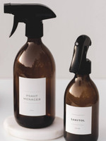 Deux bouteilles pulvérisateur en verre ambré à gâchettes noires, étiquettes Pshiit ménager sur un dessous de plat en marbre et Sanytol 250 ml