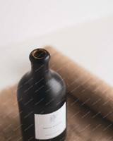 Gros plan du goulot d'une bouteille huilier en grès noir, ouverture beige non émaillée, sur une toile de jute enroulée