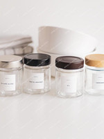 Quatre pots à épices ronds en verre à couvercles argent, noir, marron et bois, étiquettes Epices Poivre blanc, Ras el hanout, Ail et Curcuma