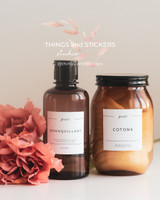 Étiquettes de salle de bain : flacon en verre ambré Démaquillant et bocal ambré Cotons, mention Beauté, à côté de roses corail