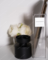 Étiquette de classeur Appartement Administration sur un porte-revues transparent garni de dossiers, devant un bougeoir noir et des pivoines