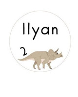 Sticker d'anniversaire rond blanc illustré d'un tricératops beige, avec le prénom Ilyan et le chiffre 2