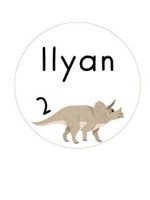 Sticker d'anniversaire rond blanc illustré d'un tricératops beige, avec le prénom Ilyan et le chiffre 2