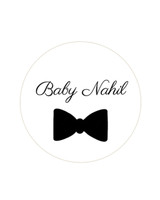 Sticker de naissance rond blanc orné d'un nœud papillon noir, avec la mention Baby Nahil en écriture calligraphique au-dessus