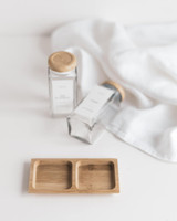 Deux pots à épices carrés à couvercles bois, l'un debout l'autre couché, devant un support en bambou vide à deux compartiments