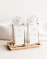 Deux pots à épices carrés à couvercles saupoudreurs transparents, étiquettes Epices Sel et Poivre, posés dans un support en bambou