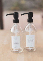 Deux flacons en verre transparent à pompes noires, étiquettes au logo Weho, Gel douche shower gel et Shampoing shampoo, mention Villa 17
