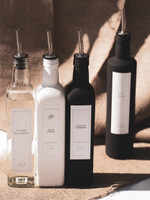Quatre huiliers carrés à becs verseurs argentés sur de la jute ensoleillée : vinaigre balsamique, huile d'olive blanc, deux noirs