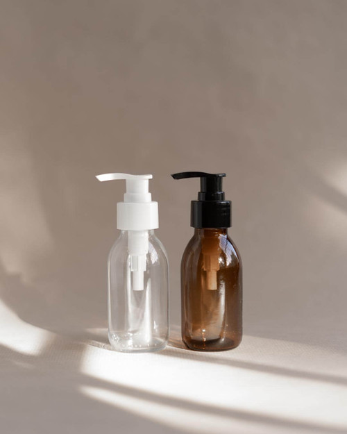 Flacon format voyage en verre 100 ml, un transparent à pompe blanche et un ambré à pompe noire