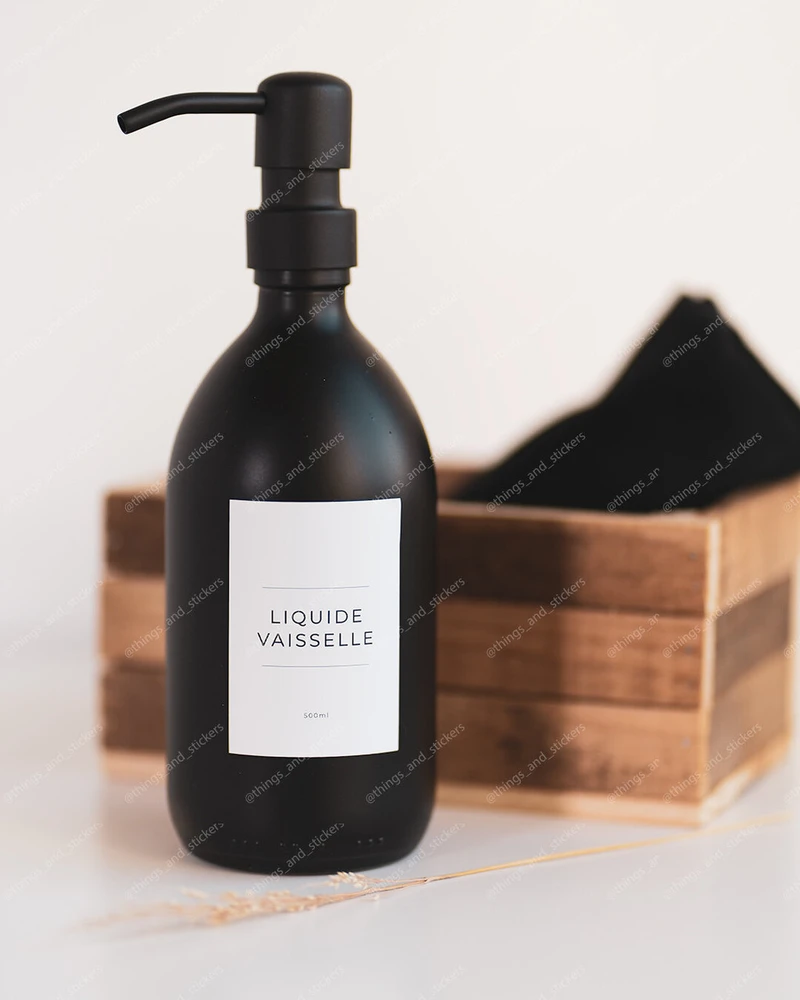 Flacon distributeur en verre noir mat à pompe noire, étiquette Liquide vaisselle, devant une cagette en bois et un linge noir
