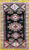 Vertical, top facing image of vintage Moroccan rug, showing the geometric pattern with many medallions in various colors of red, blue and gold.