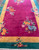 Angled, top facing image of antique Chinese carpet, showing a dimensional view of the rug in a room.