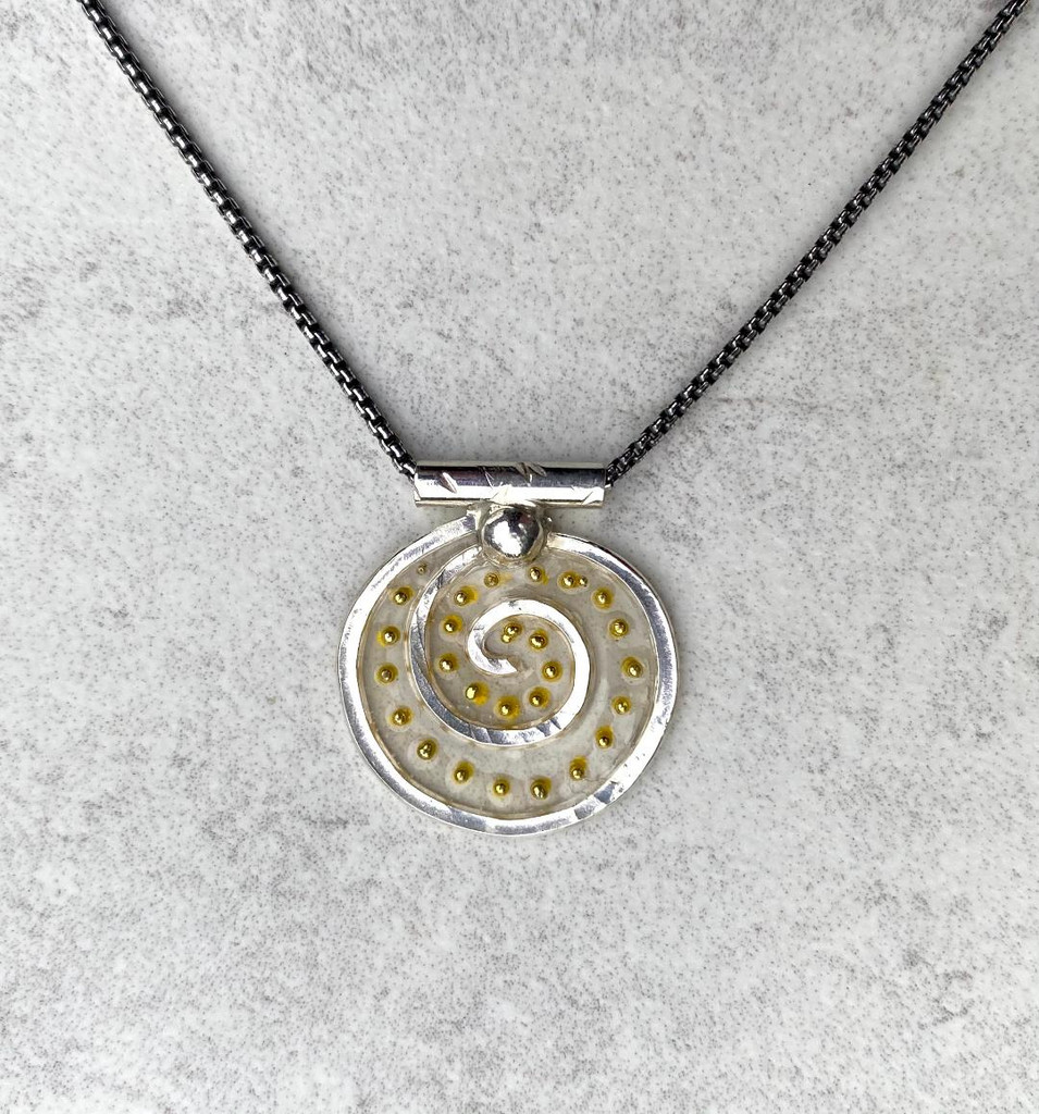 For those of us who can use some levity these days, the Lighter Than Air Spiral Circle Necklace enters stage right. So why lighter than air? The necklace features a Sterling spiral, which is in itself, a powerful image suggesting a connection to infinity, a potentially light concept. It also features translucency...pretty airy...and is embellished with little golden dots which suggest, what else(?)-- light. So all in all, it says light and lightness. The spiral measures 3/4" wide by 7/8" tall. It is suspended on a 20" Sterling chain. 
