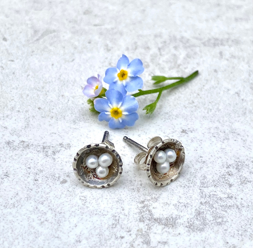It's always a thrill to discover a nest with eggs, and these earrings celebrate that. They are handcrafted out of Sterling and feature three precious freshwater pearl eggs. They measure 3/8" wide and have Sterling earring posts and backs. 