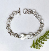 The arrowhead plant is a native marsh plant that does, indeed, have leaves shaped like arrowheads that spike out of the water. This chain bracelet is a tribute to a cool plant that is fun to find. It is  made out of Sterling. The leaf is in the center of the chain, which is made of links that whirl like water. I have used double jump rings to link these, as they add stability, and look good too. I made a toggle clasp for the bracelet, as it is one that can be linked and unlinked one-handedly. 