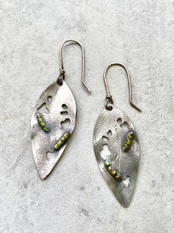 ﻿Monarch Butterflies are one of the wonders of our world. Their migration spans thousands of miles and is nothing short of a miracle. Milkweed is the only food source for their caterpillars. These earrings pay tribute to this special relationship. They feature newly hatched monarch caterpillars consuming their first meal. The earrings are hand crafted out of Sterling and the fine silver caterpillars are colored with glass enamels. They measure 3/4" by 1 3/4" not including their handmade Sterling earring wires. They are light and comfortable to wear and are the perfect gift!
