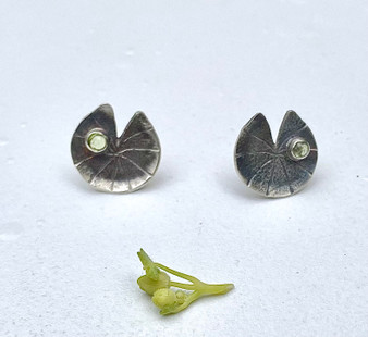 Anyone who has ever spent much time in a pond (which I highly recommend) has, no doubt, developed an appreciation of lily pads. Between their plate-like floating leaves, and their spectacular flowers, what's not to love? These Sterling stud (aka "posts" in my youth) lily pad earrings are set with a peridot each, and are carefully shaped like the real thing....leaf edges just slightly rolled, split in leaf almost to the center. To ask a favorite question yet again, what's not to love?