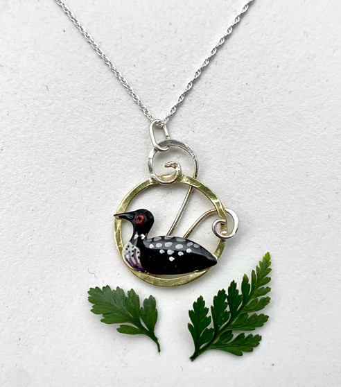 This Loon Necklace celebrates the comeback of the loon. Even with their numbers increasing, the sight of a loon is always awe-inspiring. This necklace serves as a reminder of this. It is handcrafted out of Sterling and jeweler's brass, and carefully hand-colored and sealed with jewelry-grade resin. The pendant measures 1" tall x 3/4" wide and is suspended on an 18" Sterling chain. 
